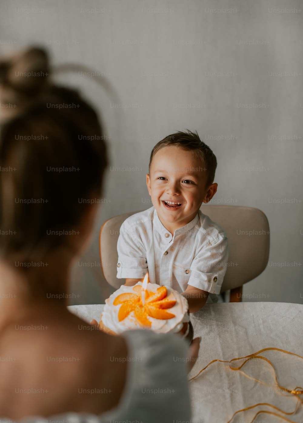 a little boy sitting at a table with a bowl of oranges