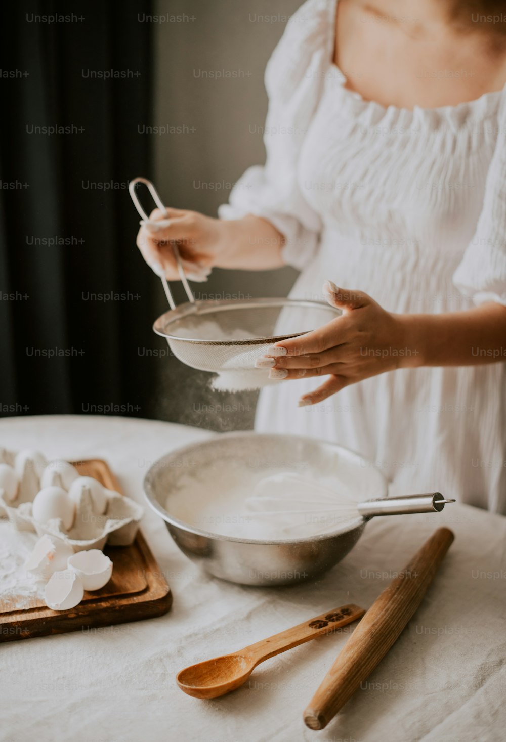 a woman in a white dress mixing ingredients in a bowl