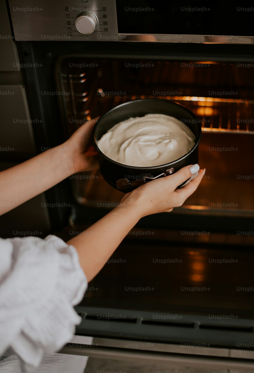 a person holding a pan of food in front of an oven