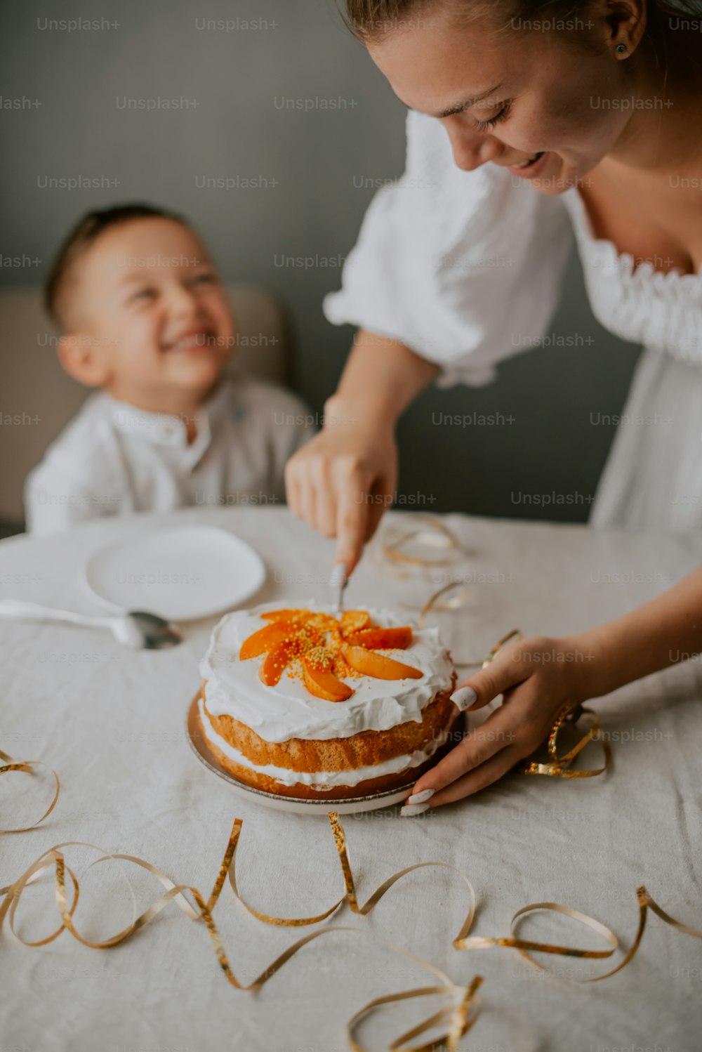 a woman cutting a cake next to a baby