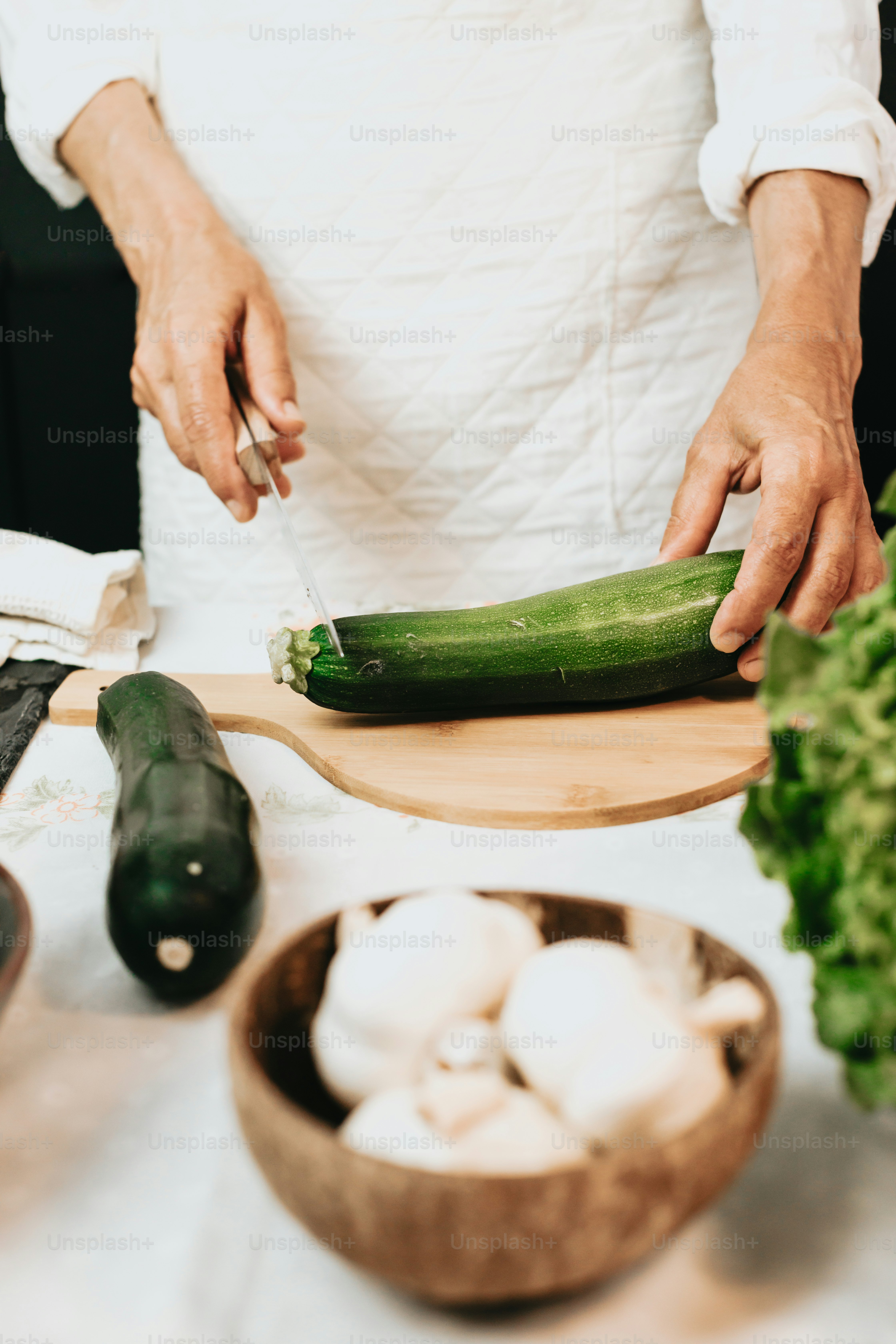 eine Person, die eine Gurke auf einem Schneidebrett schneidet