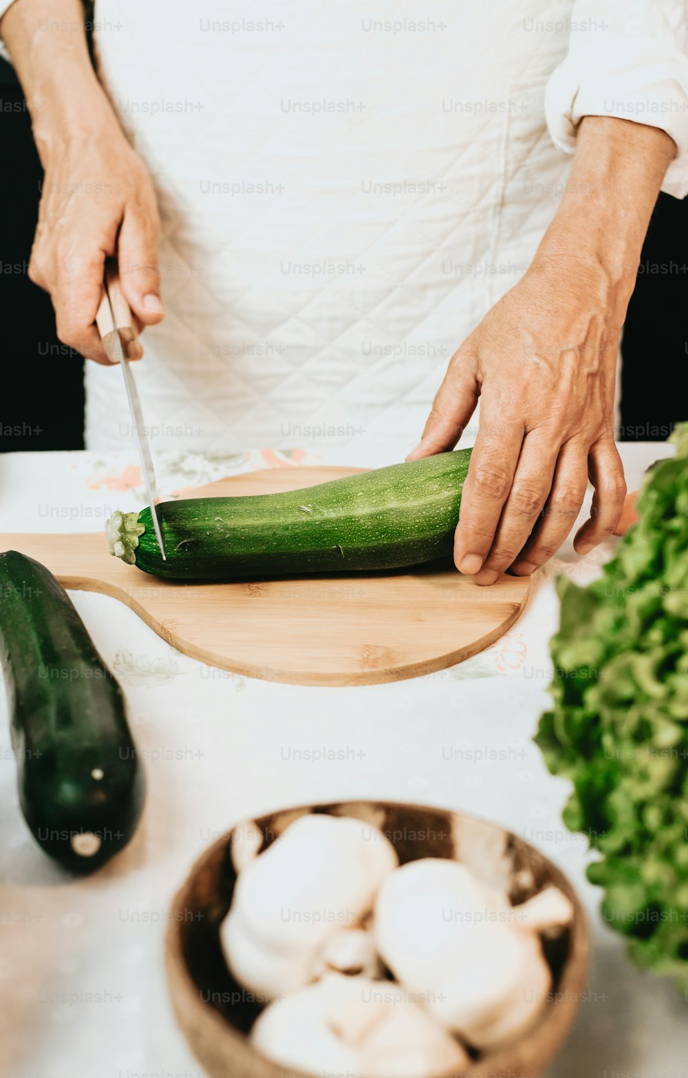 a person cutting up a cucumber on a cutting board
