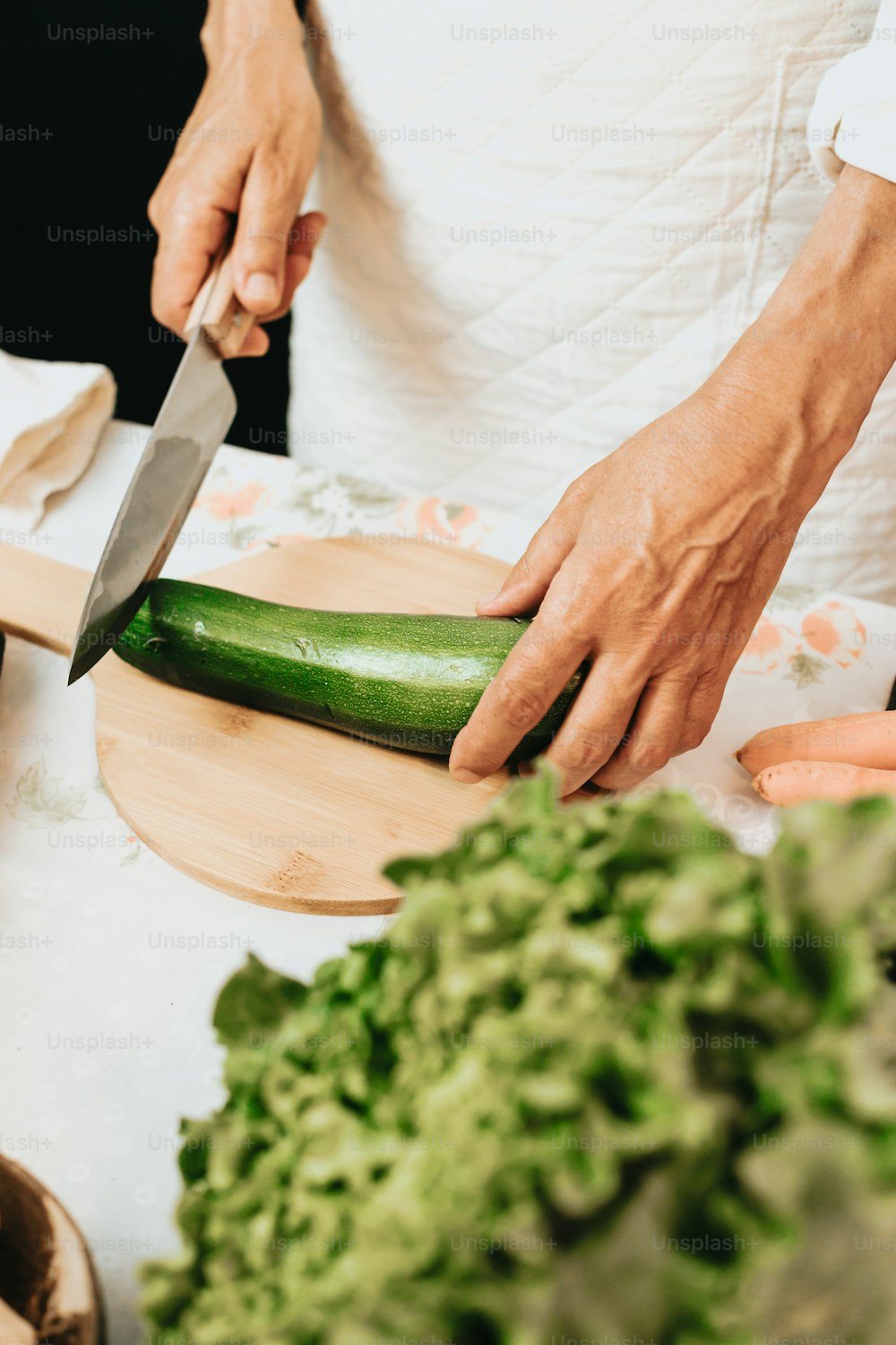 a person cutting a cucumber on a cutting board