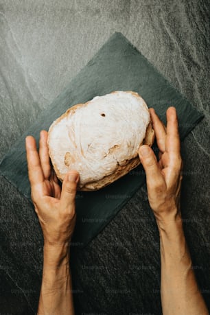 a person holding a piece of bread on top of a cloth