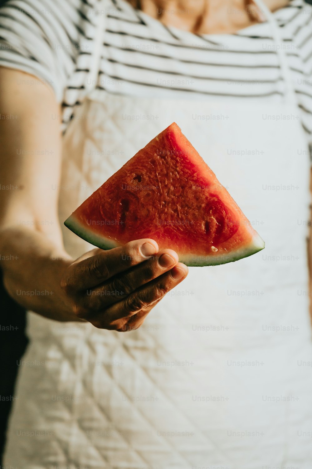 eine Person, die ein Stück Wassermelone in der Hand hält