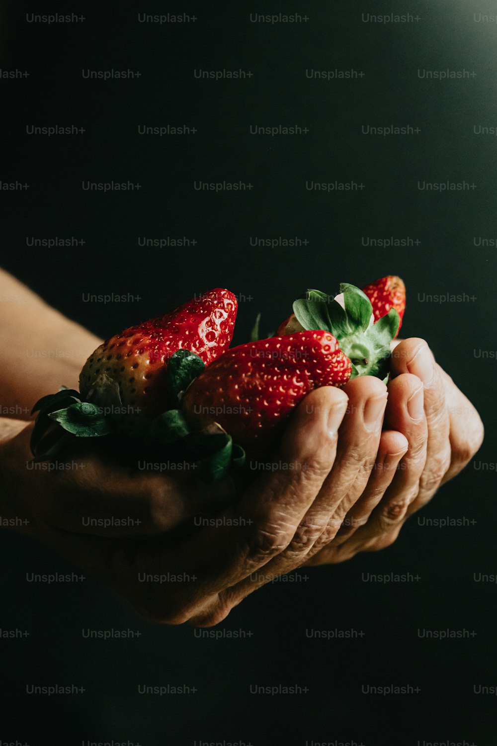 eine Person, die einen Strauß Erdbeeren in den Händen hält
