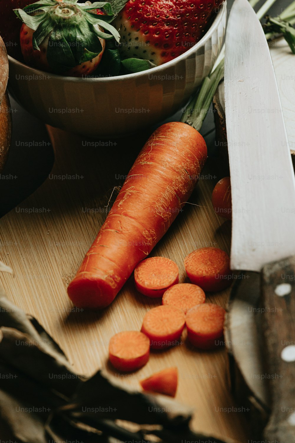 a bowl of carrots and a knife on a cutting board