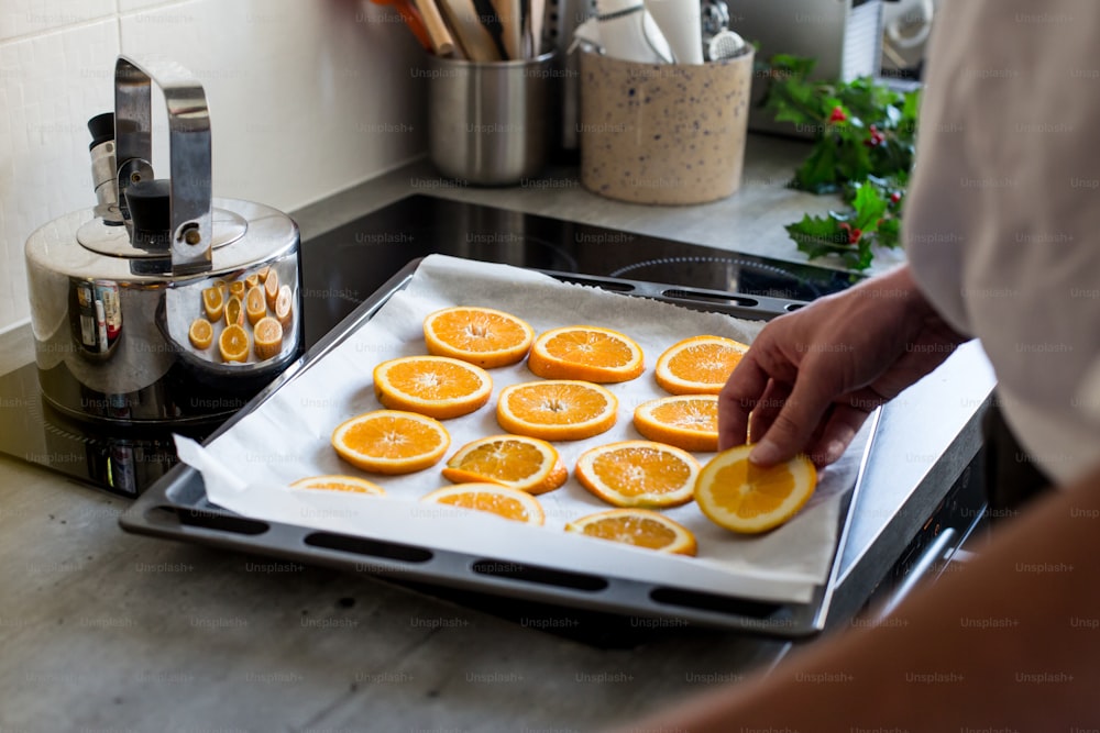 a person is putting orange slices on a pan