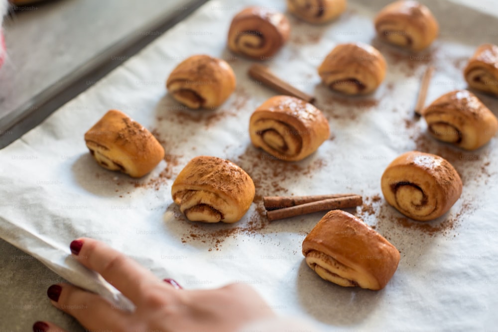 cinnamon rolls on a baking sheet with cinnamon sticks