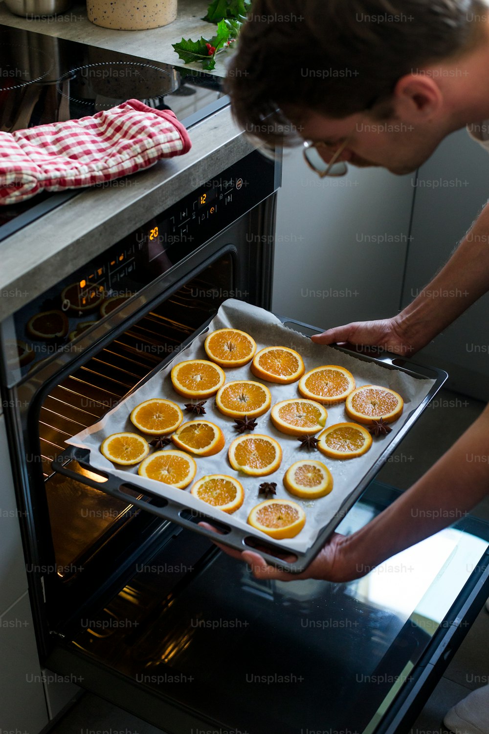 a man taking a tray of oranges out of the oven