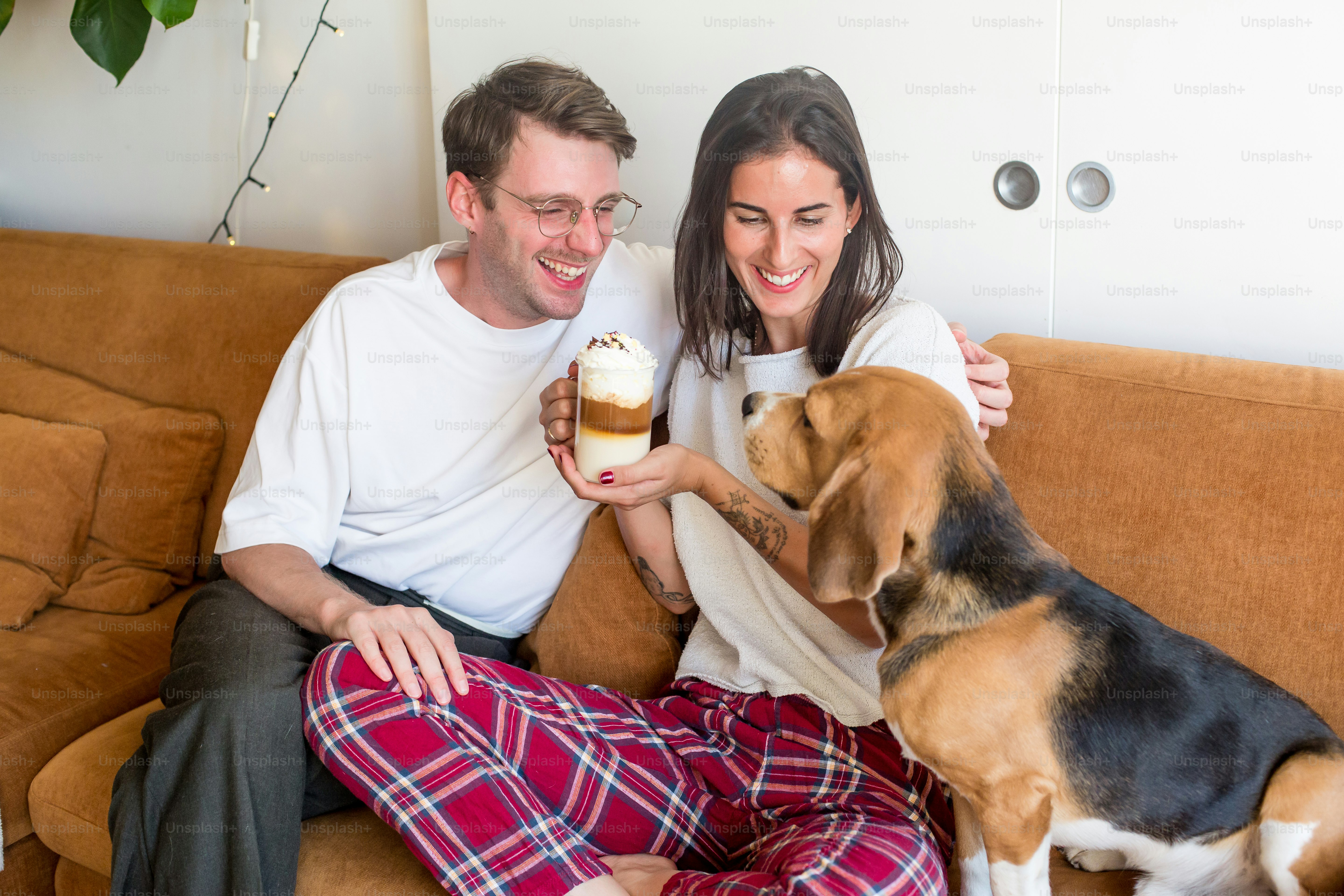 Un hombre y una mujer sentados en un sofá con un perro
