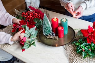 Una mujer decorando una mesa de Navidad con velas y poinsettis