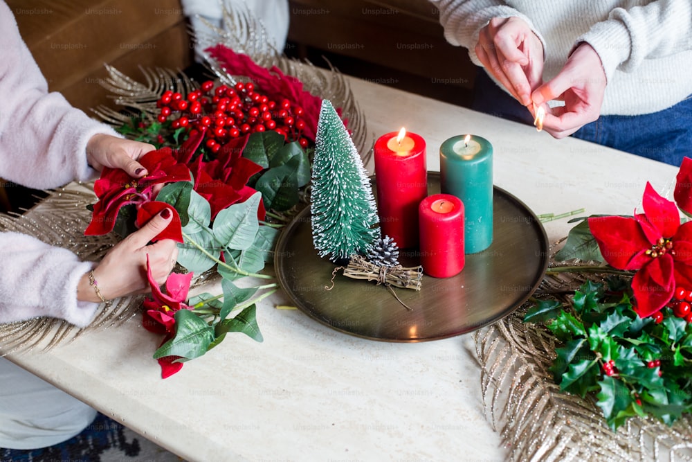 a woman decorating a christmas table with candles and poinsettis