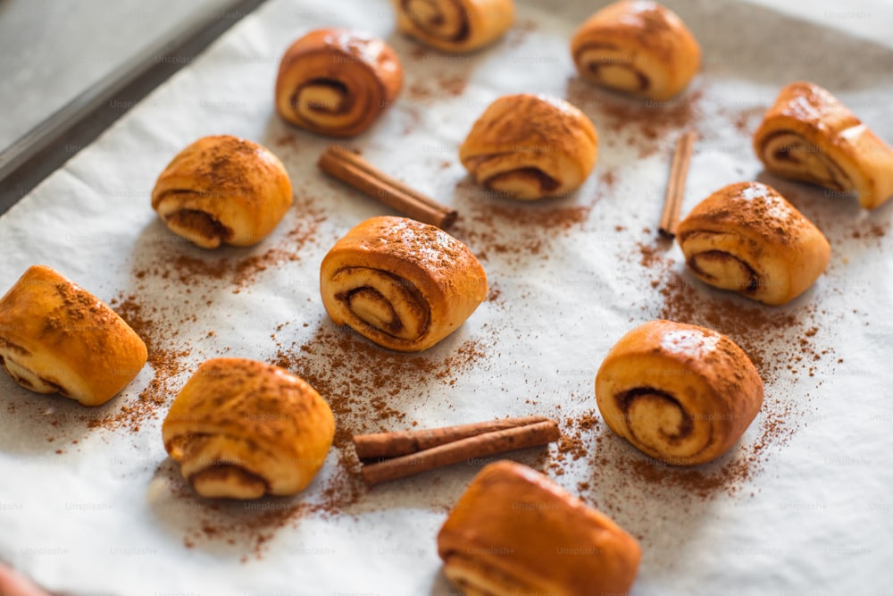 cinnamon rolls on a baking sheet with cinnamon sticks