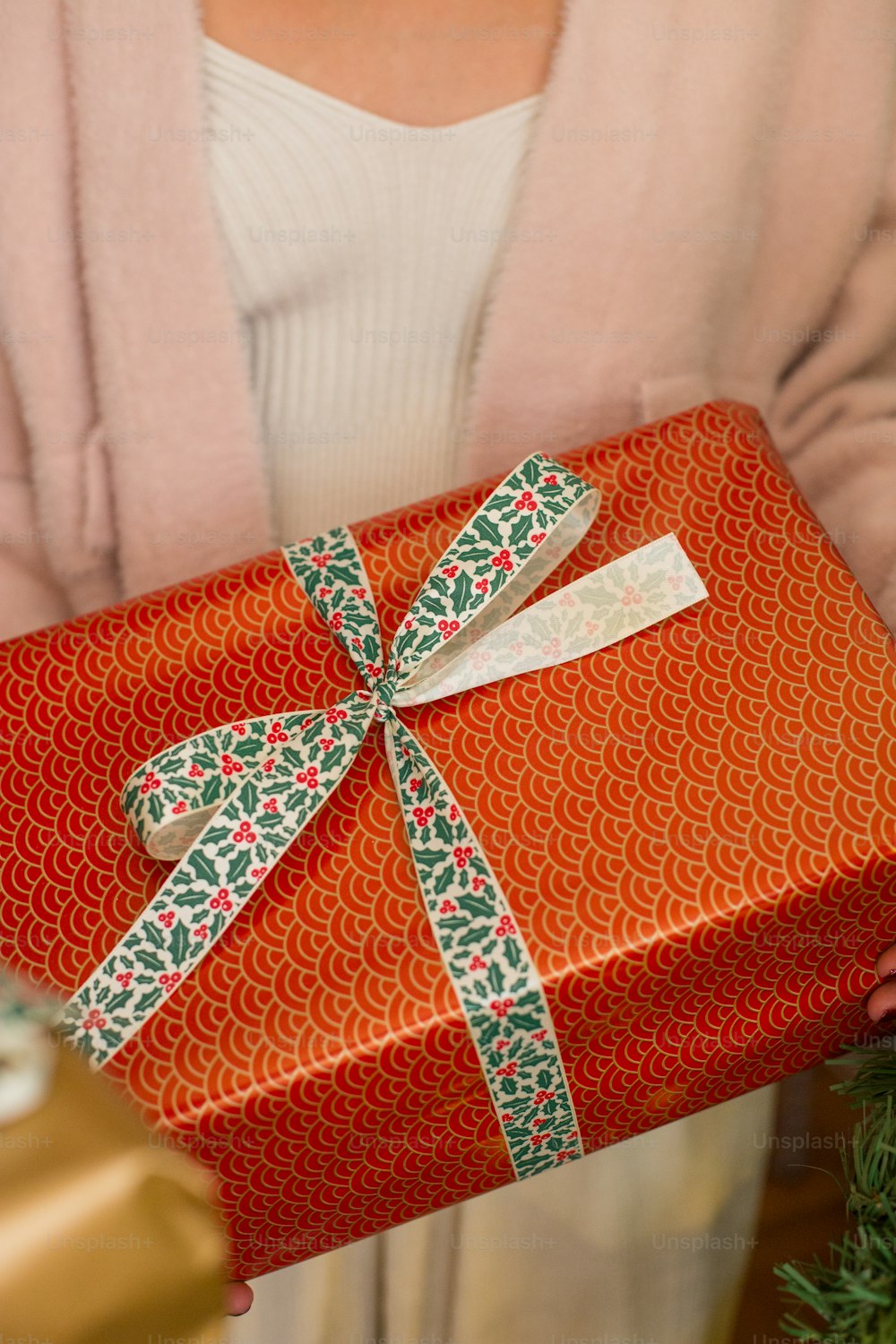 a woman holding a red present wrapped in green and red paper