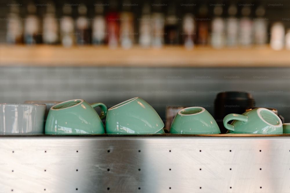 a row of tea cups sitting on top of a metal shelf