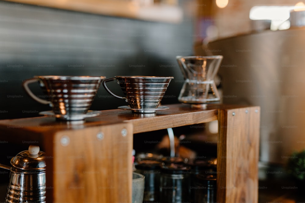 a wooden table topped with cups and a coffee pot