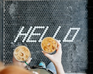 a person holding two bowls of food in front of a sign