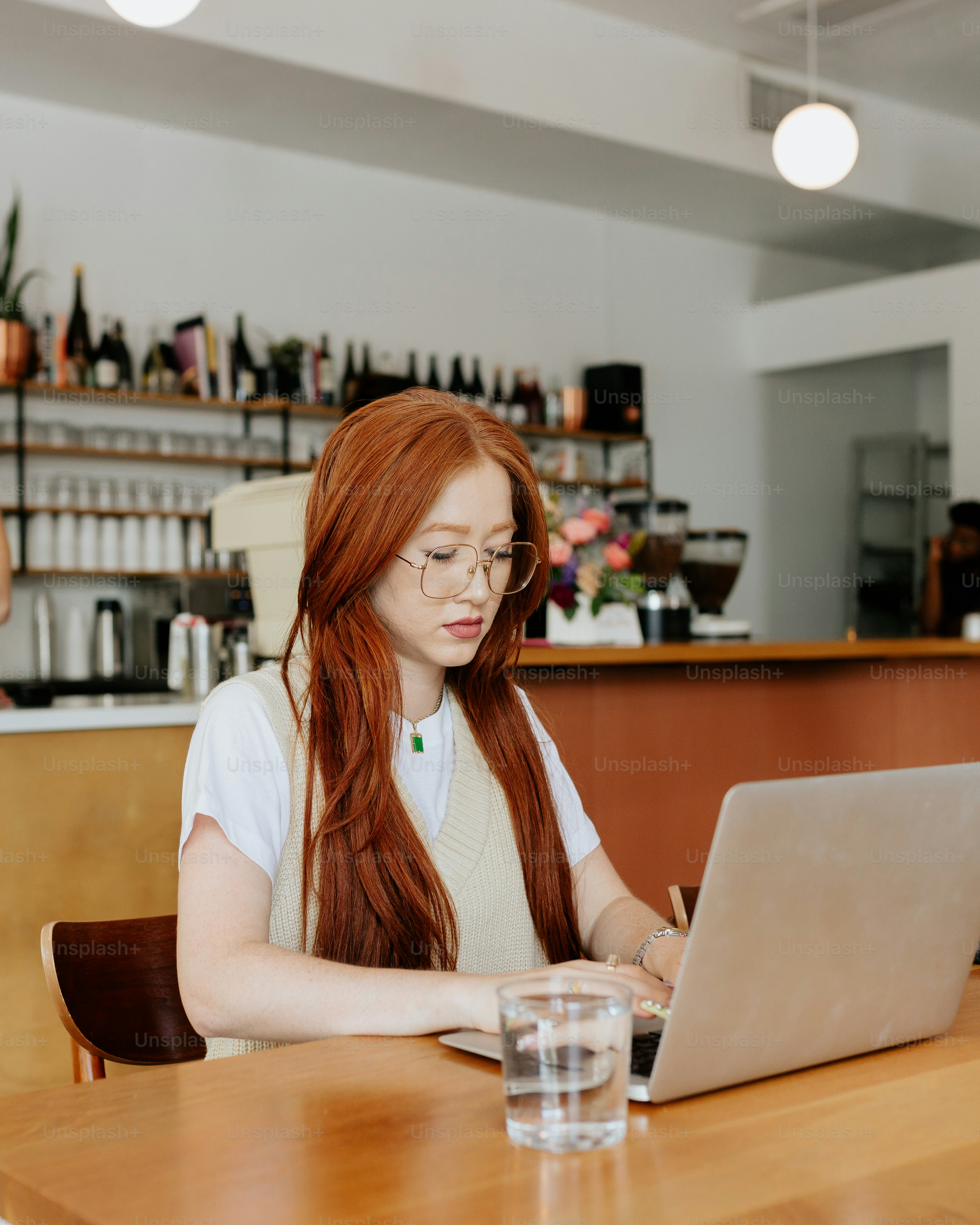 A woman sitting at a table using a laptop computer photo – Remote ...