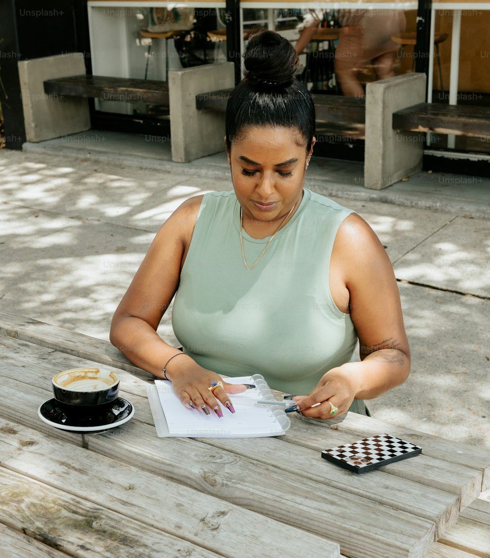 a woman sitting at a picnic table writing on a piece of paper