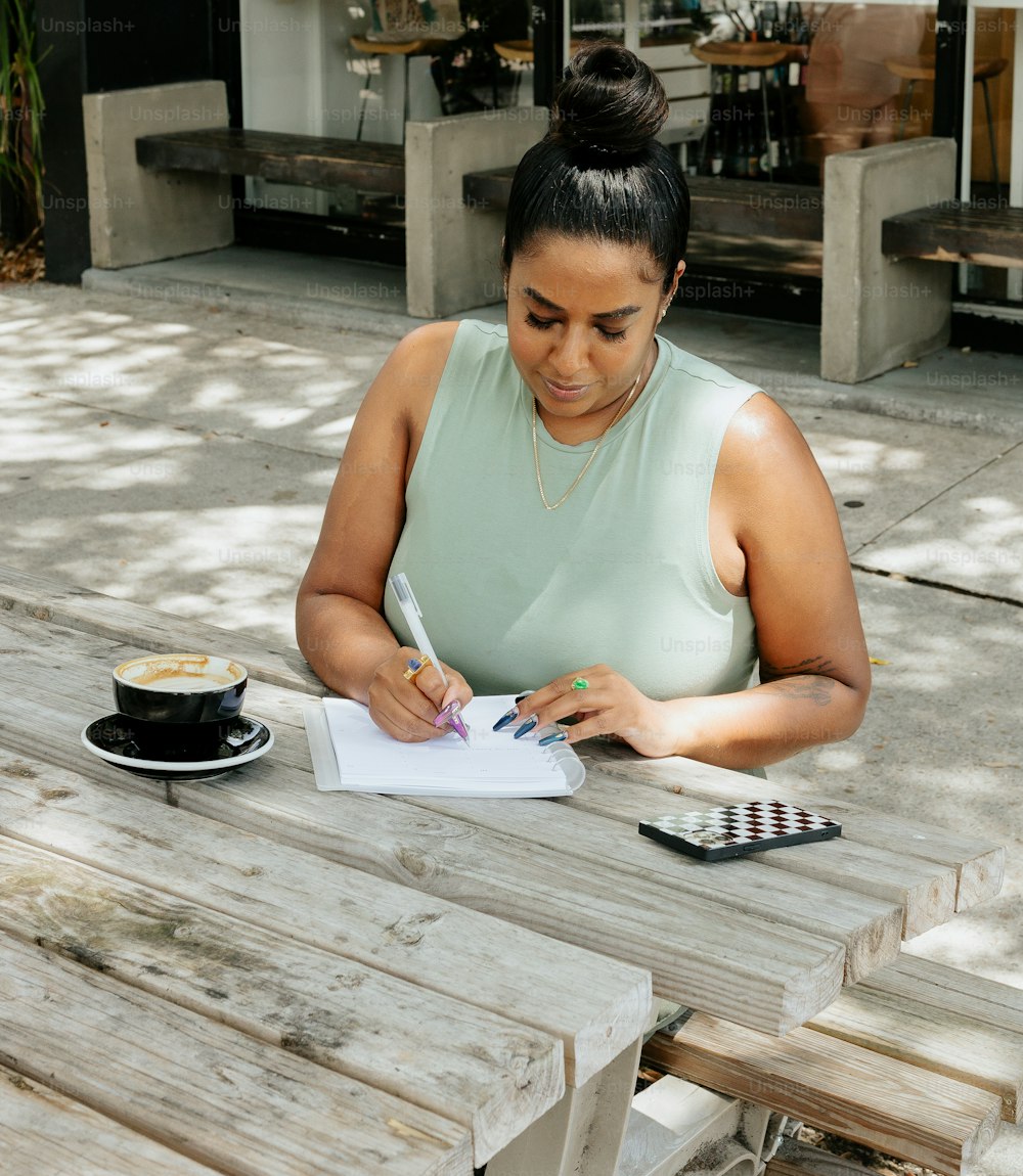 uma mulher sentada em uma mesa escrevendo em um pedaço de papel