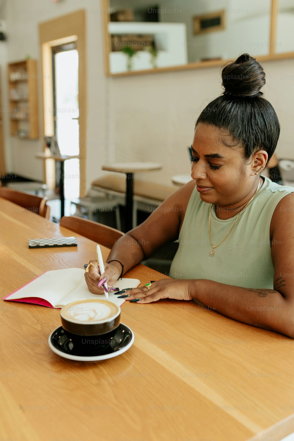 a woman sitting at a table writing in a notebook
