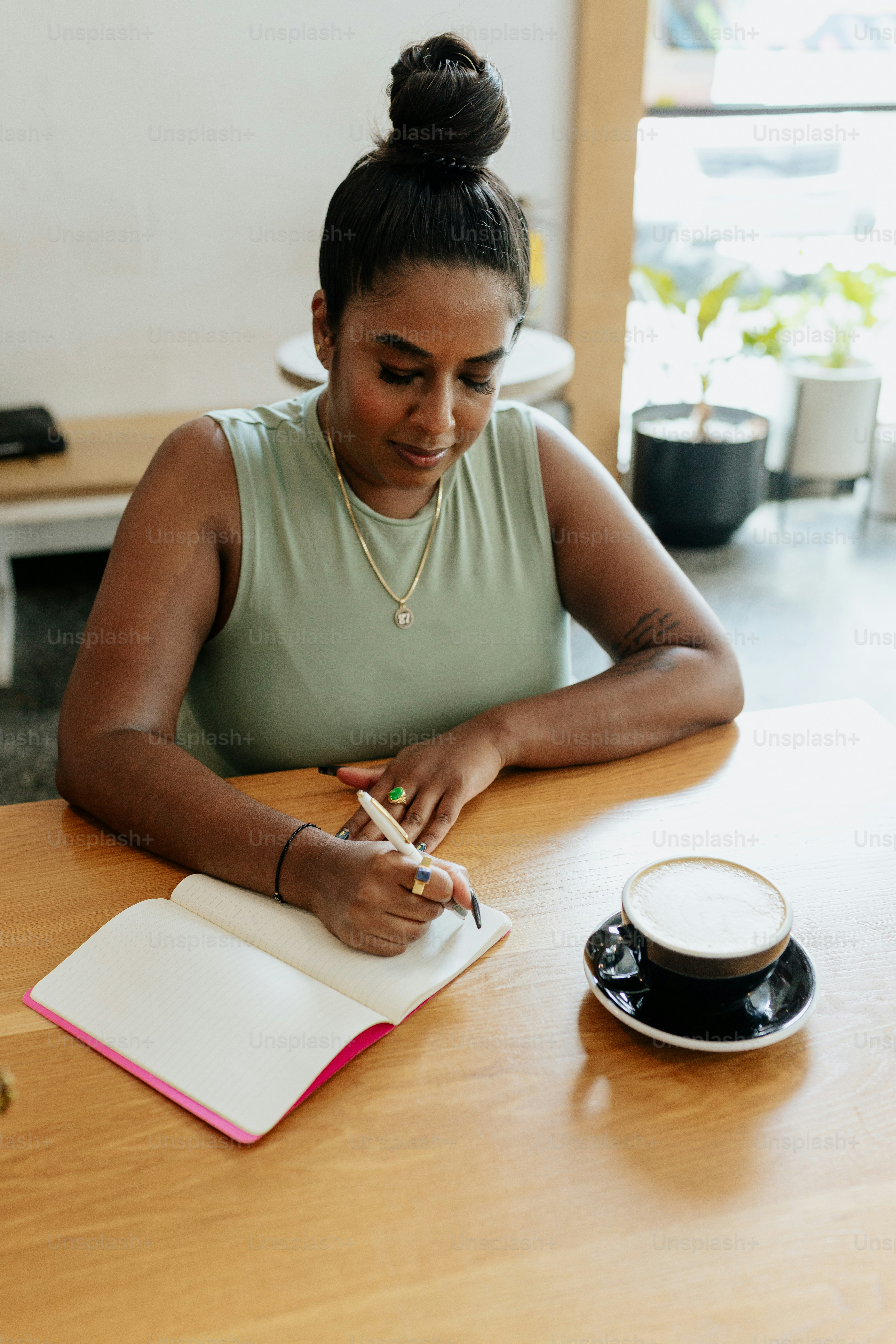 a woman sitting at a table writing in a notebook
