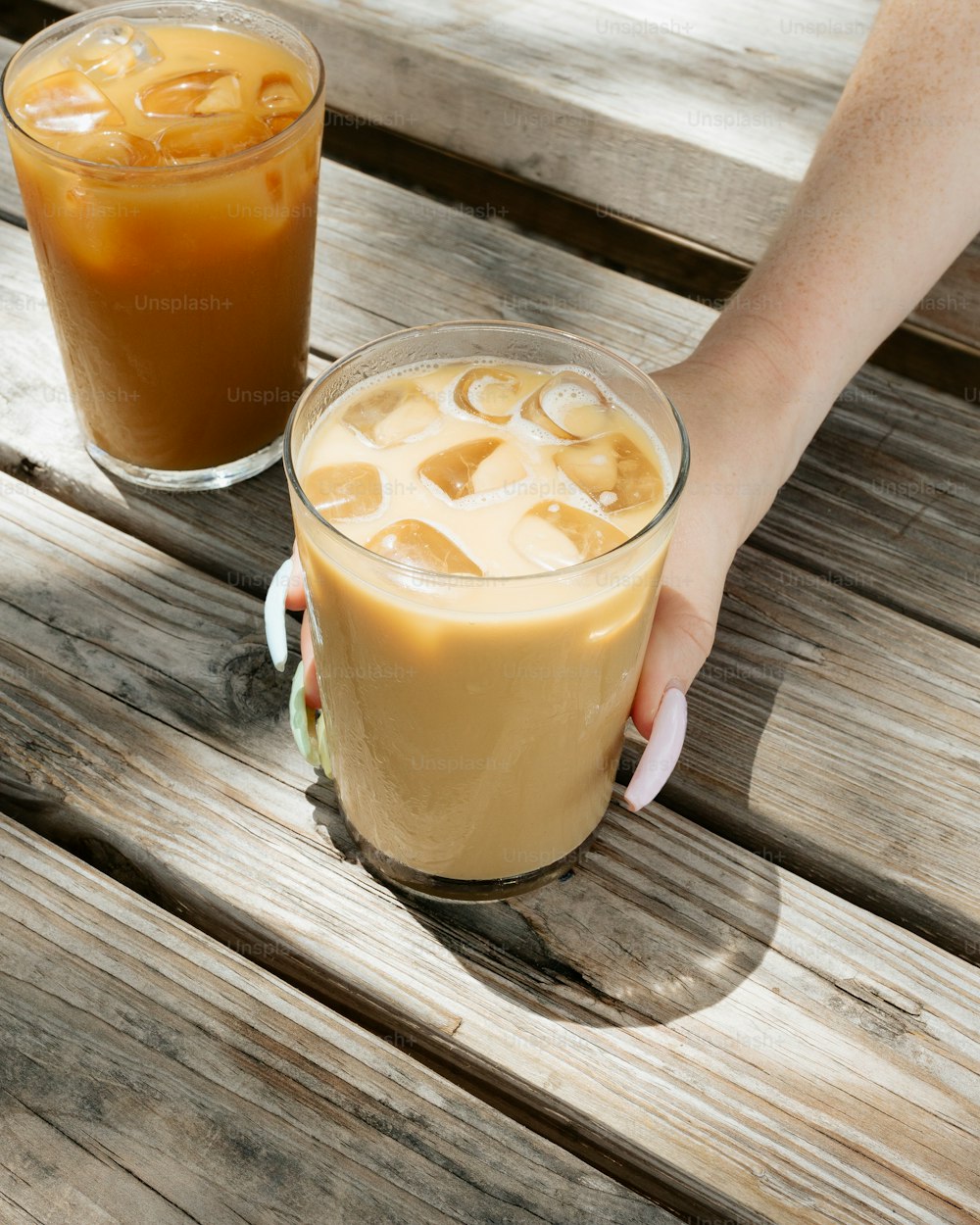 a person holding a glass of iced coffee
