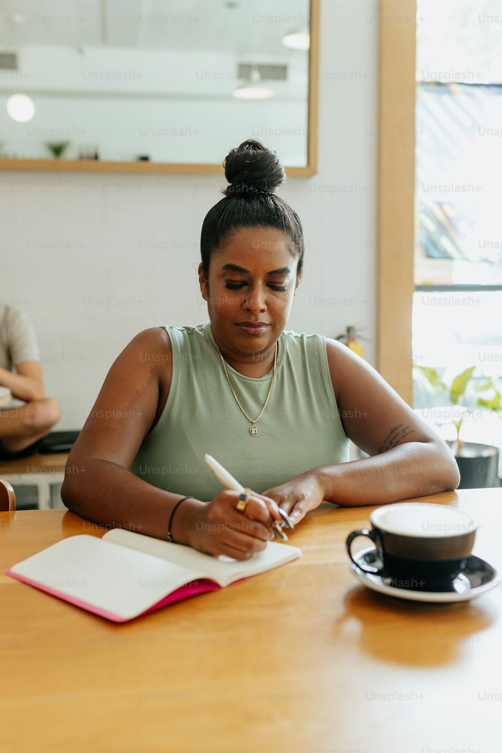 a woman sitting at a table writing in a notebook