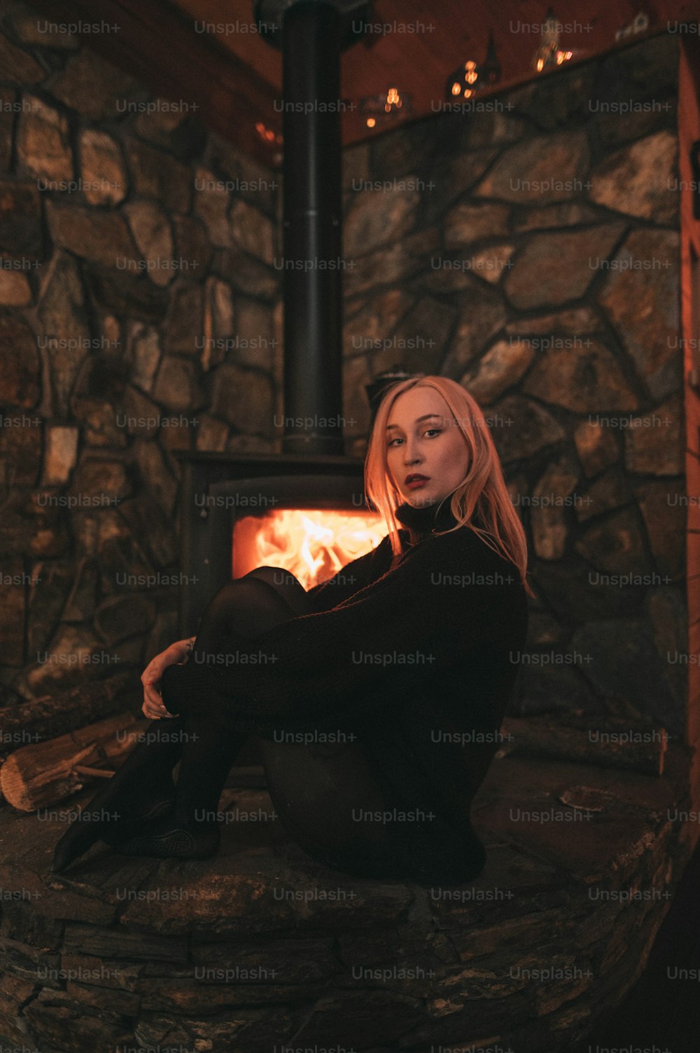 Una donna seduta davanti a una stufa a legna