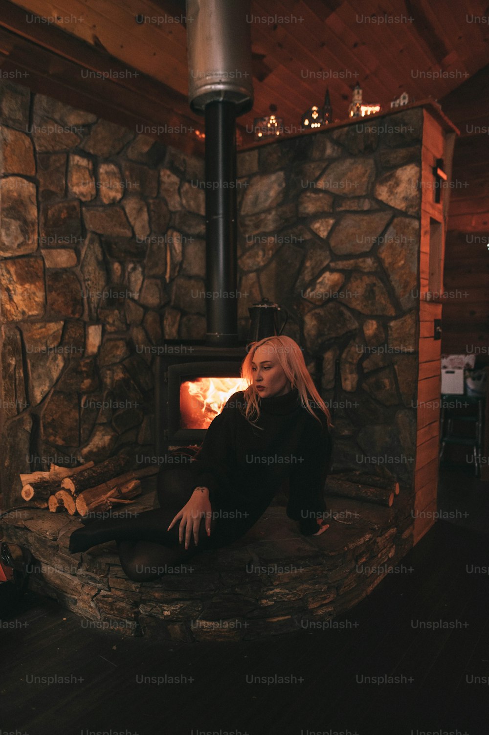 a woman sitting in front of a wood burning stove