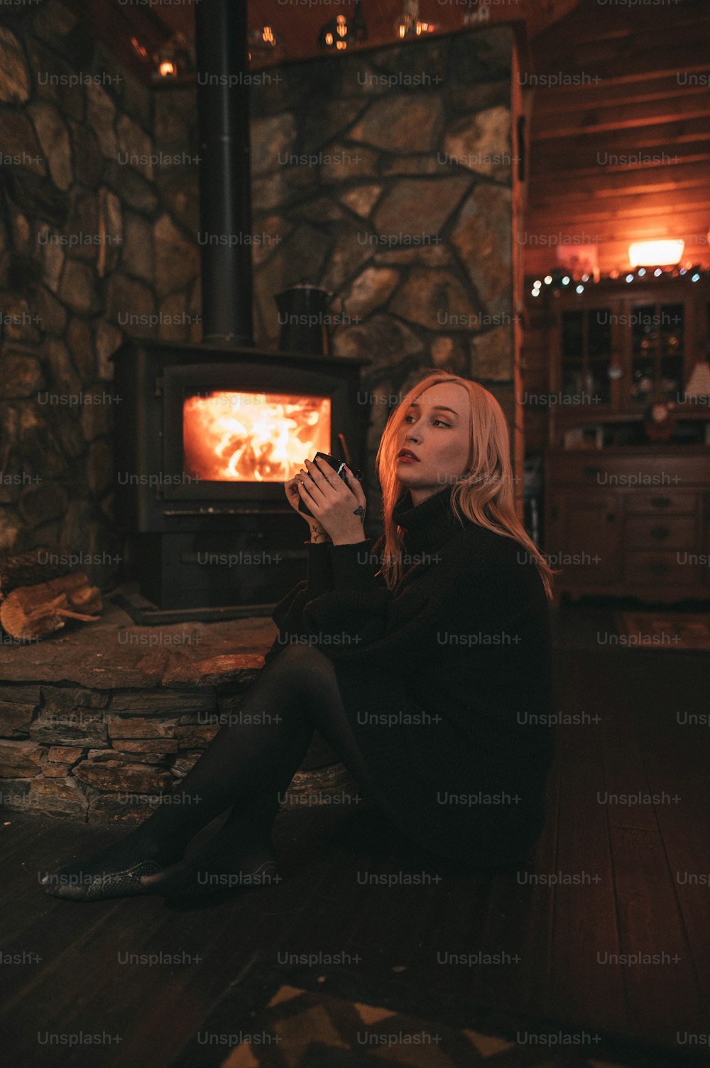 a woman sitting on the floor in front of a wood stove