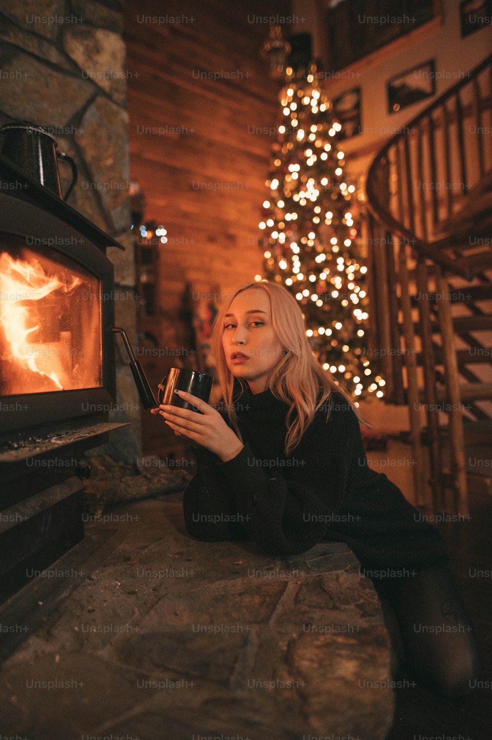 a woman sitting in front of a fireplace holding a glass of wine