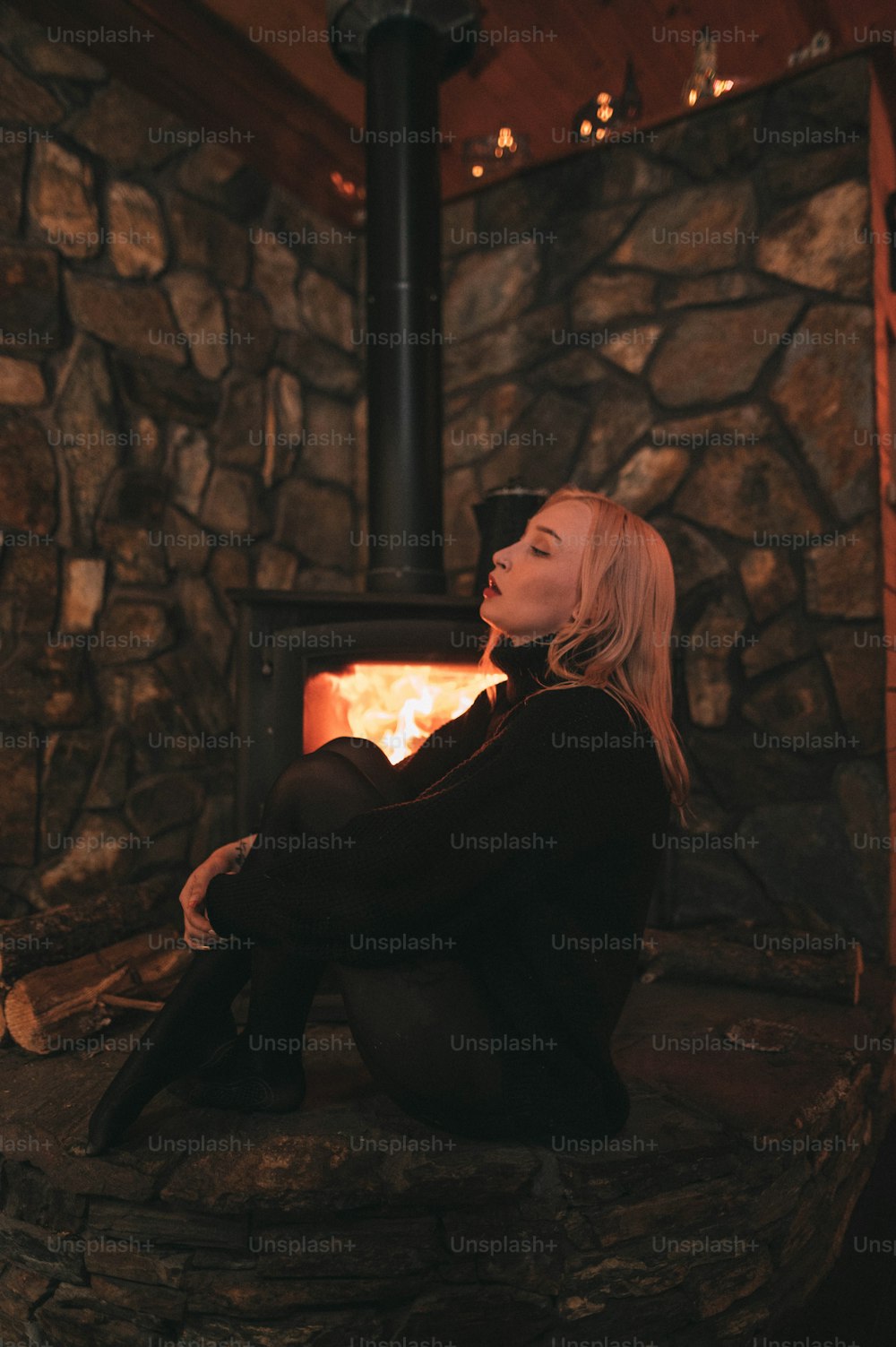 a woman sitting in front of a wood stove
