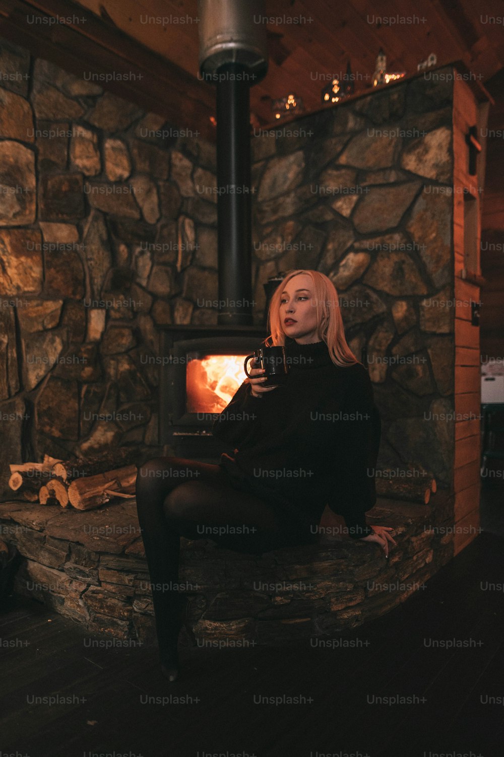 a woman sitting in front of a wood burning stove