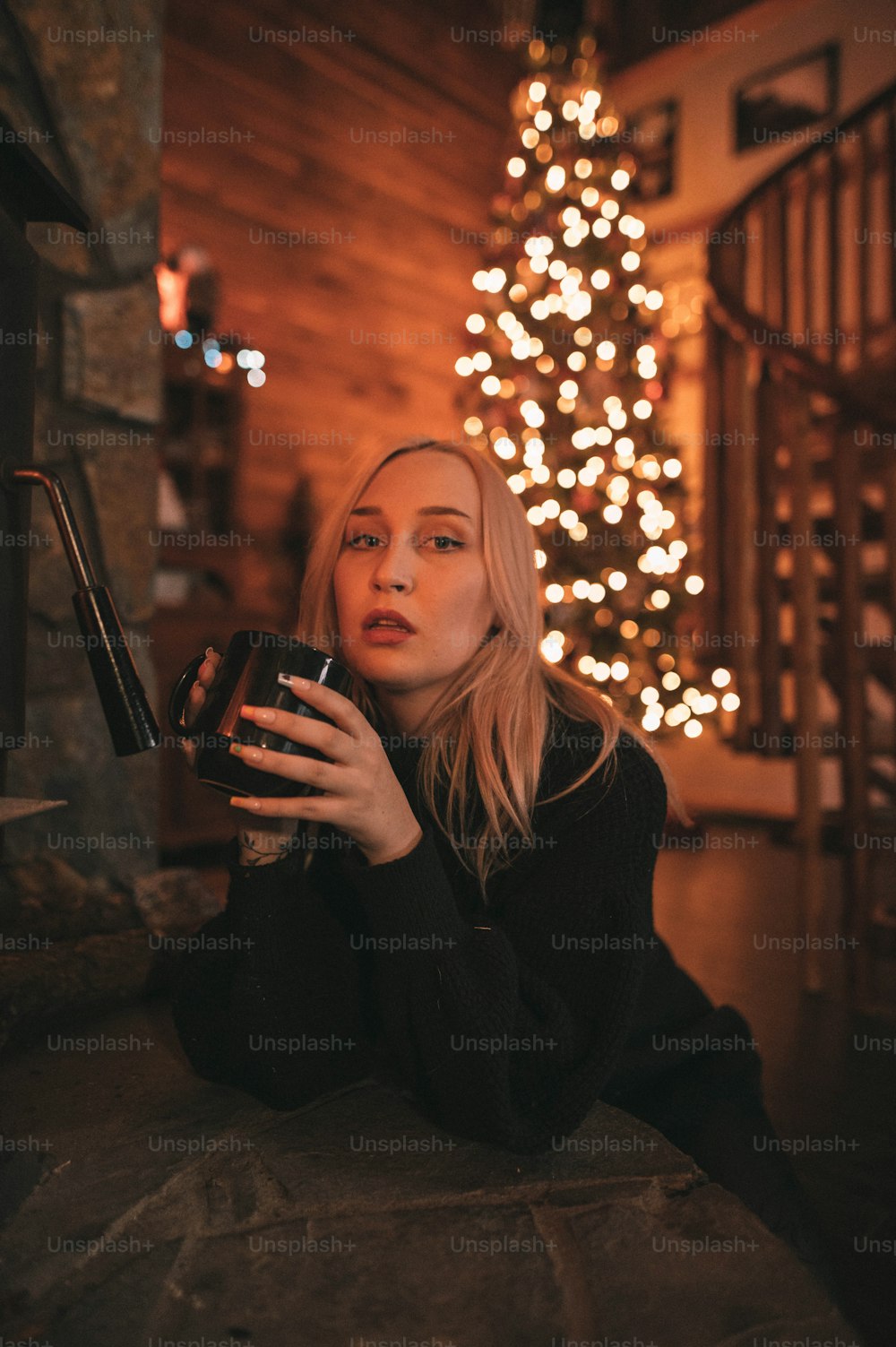 Una donna seduta davanti a un albero di Natale che tiene un bicchiere di vino