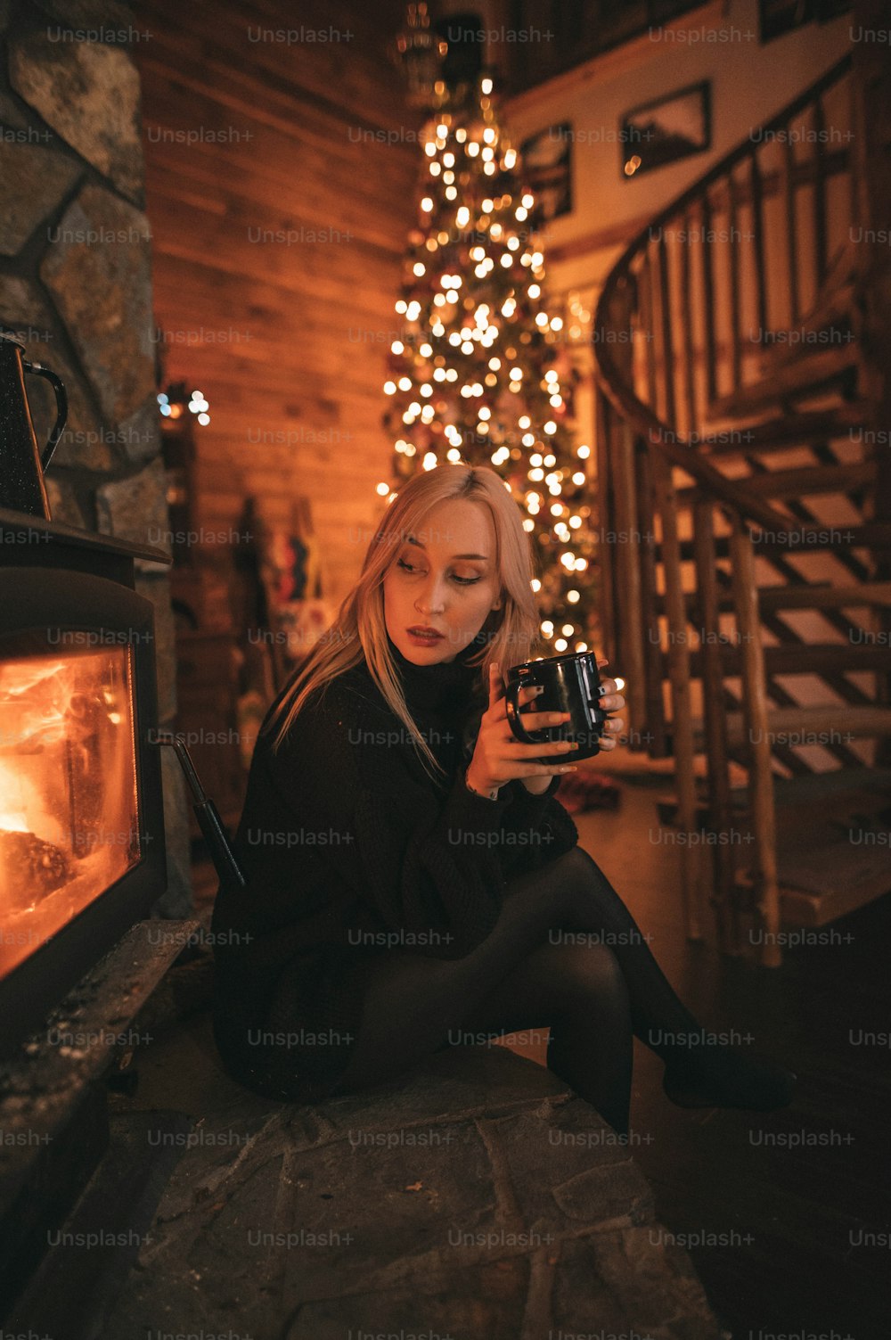 a woman sitting in front of a fireplace holding a camera