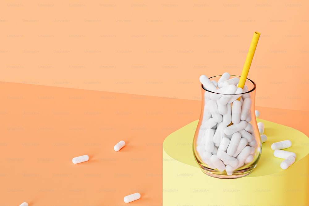 a glass filled with white pills and a yellow straw