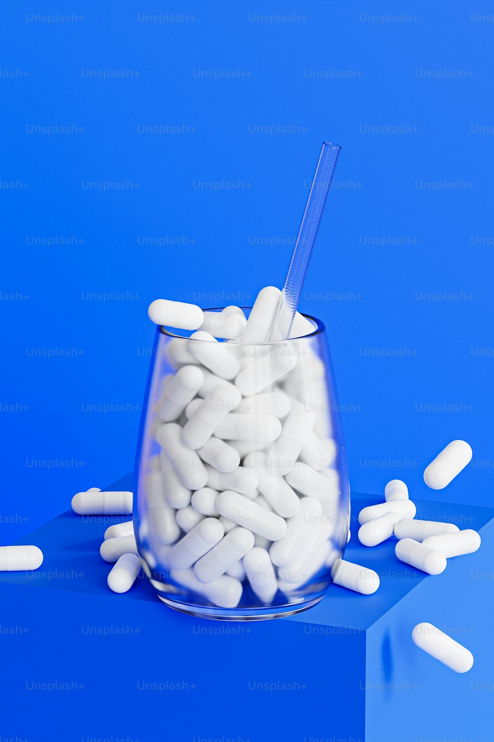 a glass filled with white pills sitting on top of a blue surface