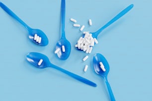 a group of blue spoons with white pills on them