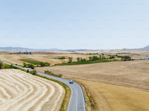 um carro dirigindo por uma estrada rural no meio de um campo de trigo