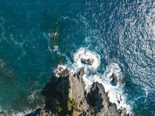 an aerial view of the ocean and rocks