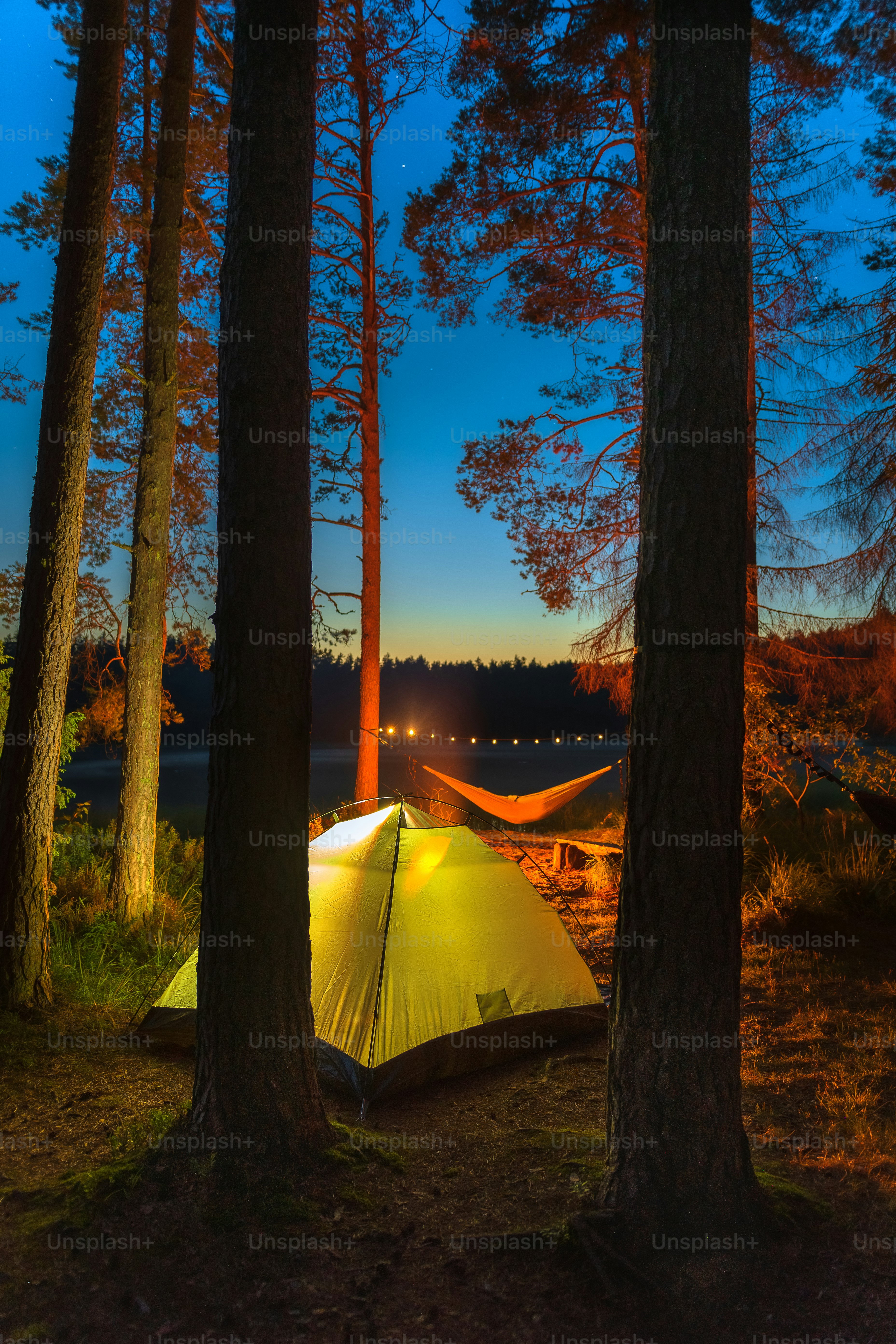 a tent pitched up in the woods at night