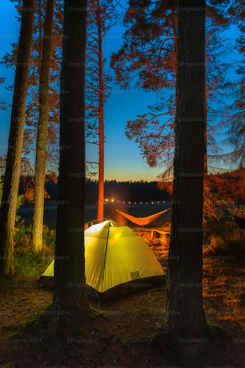 a tent pitched up in the woods at night