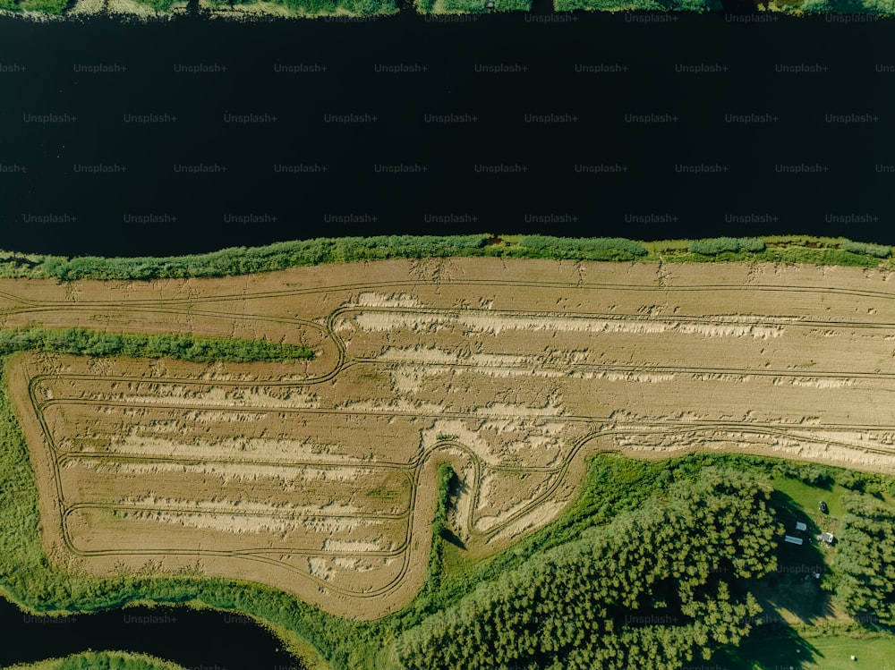 an aerial view of a dirt field near a body of water