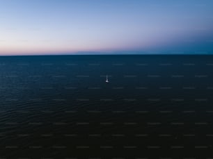 a lone sailboat in the middle of the ocean