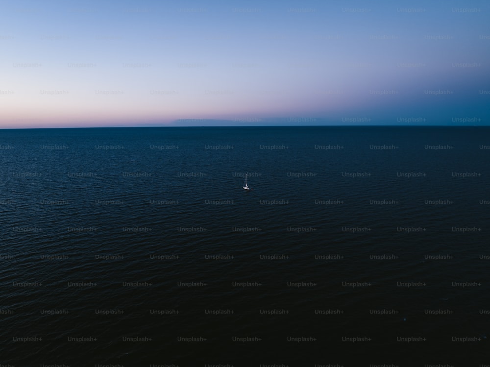 a lone sailboat in the middle of the ocean