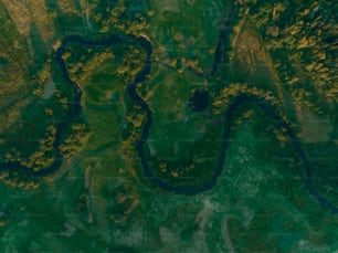 an aerial view of a river running through a lush green field