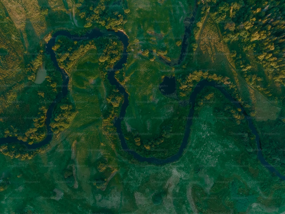 an aerial view of a river running through a lush green field