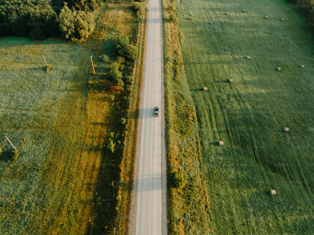 a car driving down a country road in the middle of a field